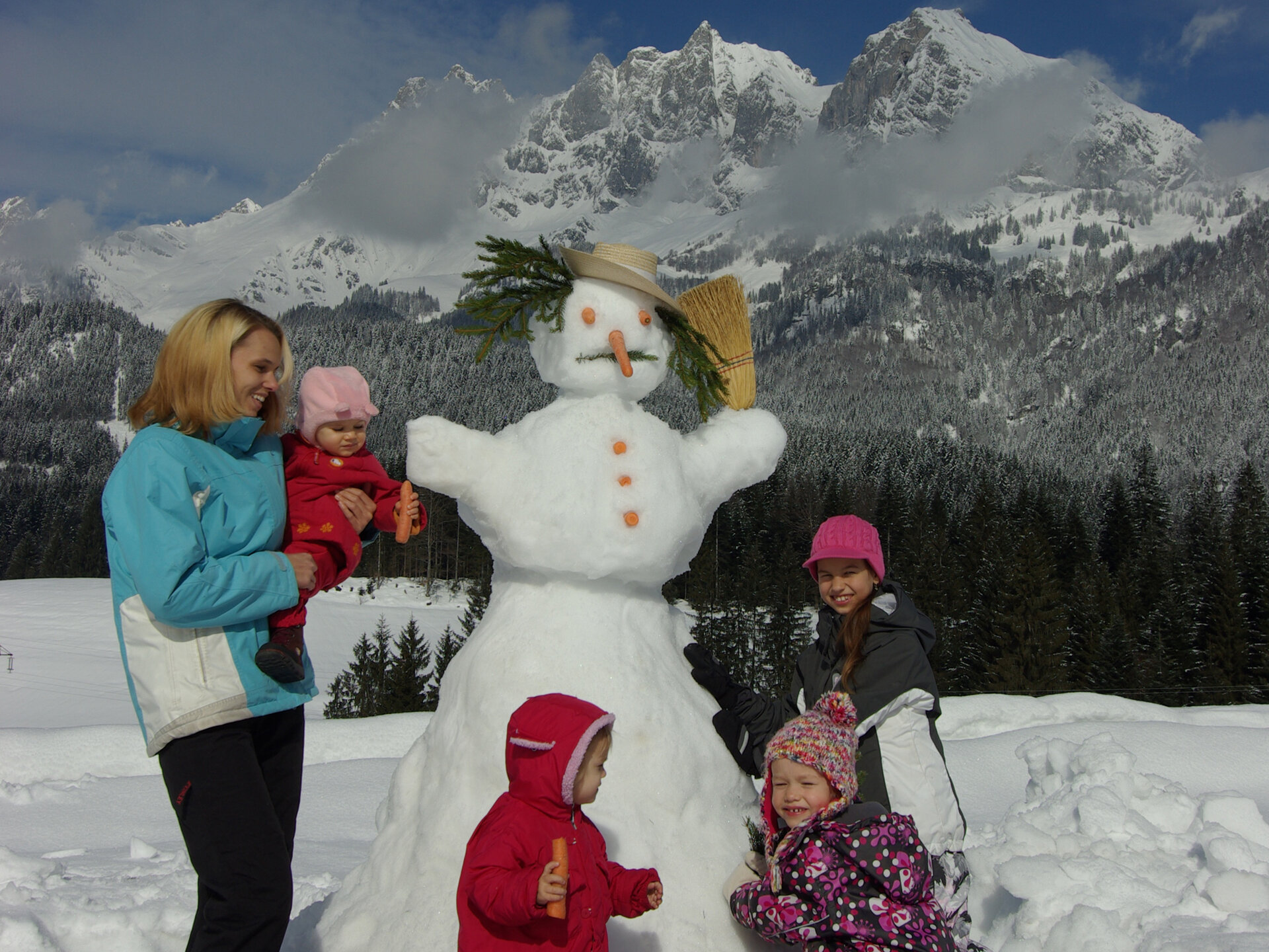 Familie im Schnee mit Schneemann
